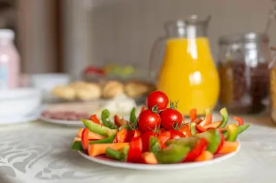 a plate of vegetables on a table with orange juice at Vrtnarjeva hiša, The Gardener's Cottage in Radovljica