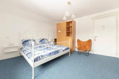 a bedroom with a white bed and a chair at Vrtnarjeva hiša, The Gardener's Cottage in Radovljica