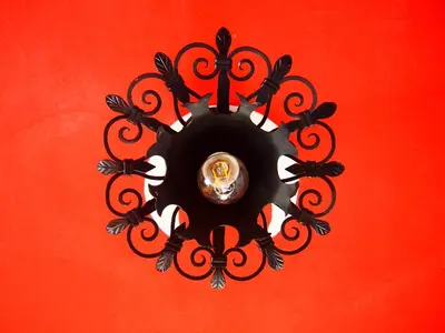 a circular chandelier is hanging on a red wall at Tony's Old Farm in Begunje na Gorenjskem