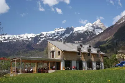 a building with snow covered mountains in the background at Apartments Jojo in Bovec