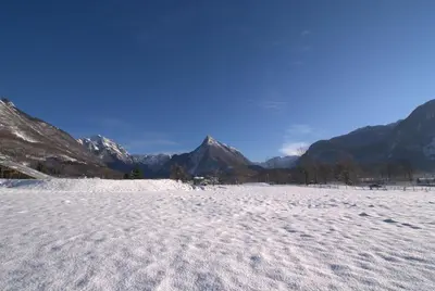 a snow covered field with mountains in the background at Apartments Jojo in Bovec
