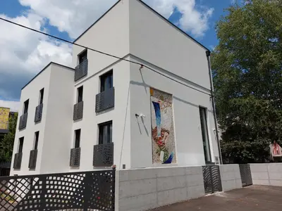 a white building with windows and a fence at Bed & Breakfast Mozaik in Ljubljana