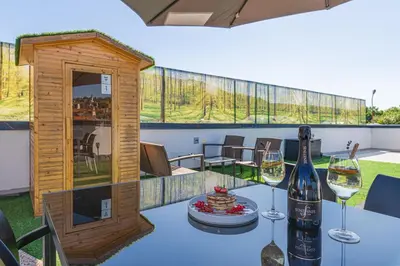 a table with a bottle of wine and two glasses at Rooftop Home With Whirlpool & Sauna - Happy Rentals in Trebnje