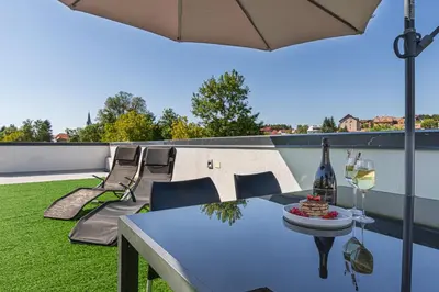 a table with a glass of wine on a balcony at Rooftop Home With Whirlpool & Sauna - Happy Rentals in Trebnje