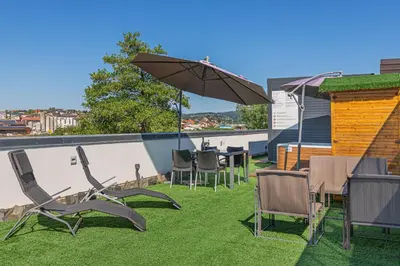 a patio with chairs and tables and an umbrella at Rooftop Home With Whirlpool & Sauna - Happy Rentals in Trebnje