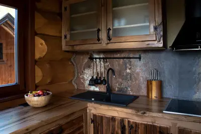 a kitchen with wooden cabinets and a sink and a counter at Brunarica Biopark -Log house Biopark in Grosuplje