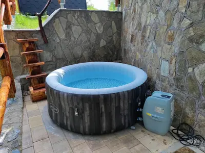 a large wooden hot tub in a stone wall with aperature at Brunarica Biopark -Log house Biopark in Grosuplje