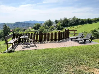 a wooden deck with benches and a table on it at Holiday house Aronija in Šmarje pri Jelšah