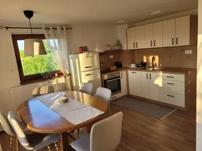 a kitchen with a wooden table and a table and chairs at Holiday house Aronija in Šmarje pri Jelšah