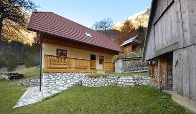 a house with a porch and a stone wall at Zadnjica Holiday House in Soča