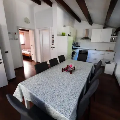 a kitchen with a table and chairs and a kitchen with white cabinets at Apartma Rok in Plavje