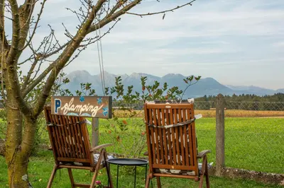 two chairs sitting next to a tree with mountains in the background at Glamping with a view in Smlednik