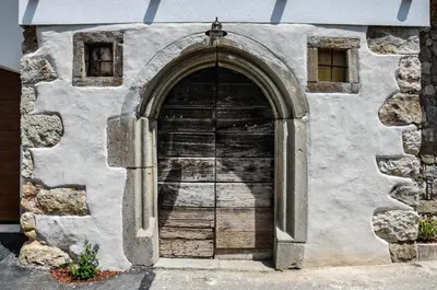 a stone building with a large wooden door at Apartmaji Tanto Malovše in Črniče