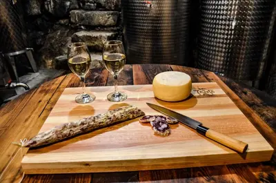 a wooden table with two glasses of wine and a knife at Apartmaji Tanto Malovše in Črniče