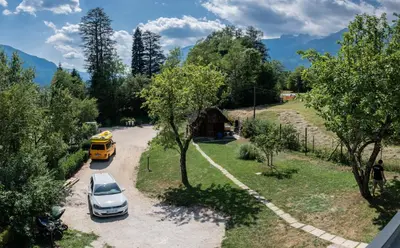 a yellow school bus and a car parked on a road at House Hiperbola & Outdoor Activities in Bovec