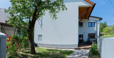 a white house with a tree in front of it at House Hiperbola & Outdoor Activities in Bovec