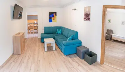 a living room with a blue couch and a table at House Hiperbola & Outdoor Activities in Bovec