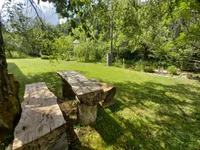 a stone bench sitting in the grass in a park at The RiverSide Chill Hostel in Bled