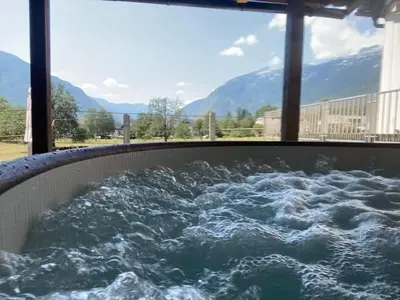 a hot tub filled with water with mountains in the background at Apartma Stres in Bovec