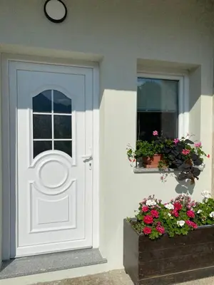 a white door on a house with a window and flowers at Apartma Stres in Bovec