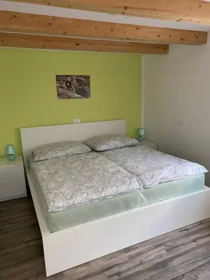 a white bed in a bedroom with a wooden ceiling at Apartma Stres in Bovec