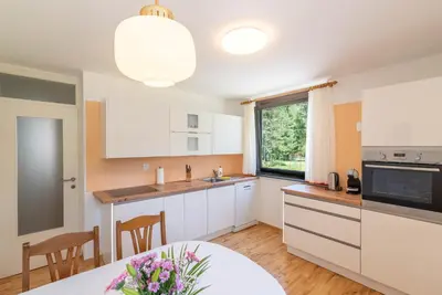a kitchen with white cabinets and a table and a window at Kranjska gora balcony apartment in Kranjska Gora
