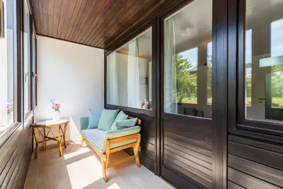 a screened porch with a chair and windows at Kranjska gora balcony apartment in Kranjska Gora
