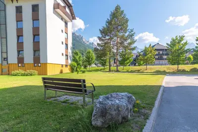 a park bench next to a rock next to a building at Kranjska gora balcony apartment in Kranjska Gora
