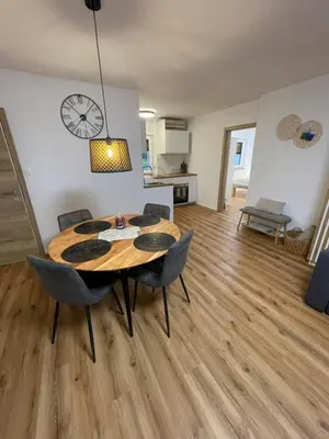 a dining room table with chairs and a clock on the wall at Apartma Guide 360 in Bovec