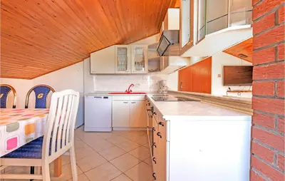 a kitchen with white cabinets and a table and chairs at Stunning Apartment In Divaca With Wifi in Divača
