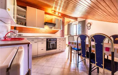 a kitchen with white cabinets and a table and chairs at Stunning Apartment In Divaca With Wifi in Divača