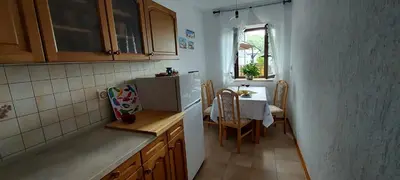 a small kitchen with a table and a refrigerator at Apartma pr' Ivani Miškorinovi in Breginj