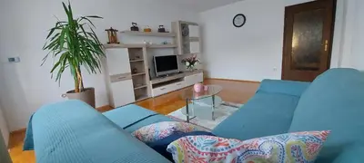 a living room with a blue couch and a tv at Apartma pr' Ivani Miškorinovi in Breginj