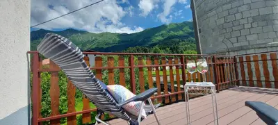 a rocking chair on a balcony with a view of mountains at Apartma pr' Ivani Miškorinovi in Breginj