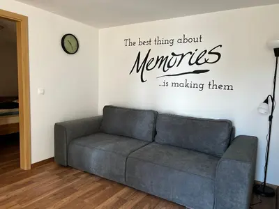 a living room with a couch and a clock on the wall at Zemva Stays - Apartma ELA in Zgornje Gorje