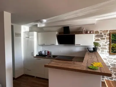 a kitchen with white cabinets and a wooden counter top at Zemva Stays - Apartma ELA in Zgornje Gorje