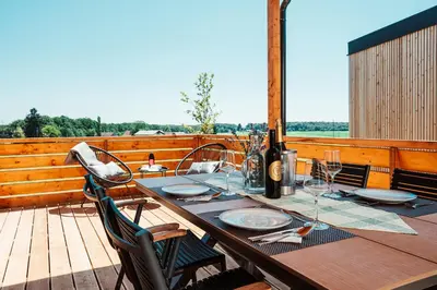 a wooden table with wine glasses on a deck at Wine paradise Glavinič in Miklavž pri Ormožu