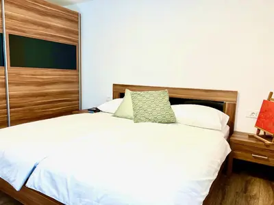 a bedroom with a white bed with a wooden headboard at Apartment ZEN in Zgornje Škofije