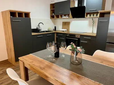 a kitchen with a wooden table with wine glasses at Apartment ZEN in Zgornje Škofije