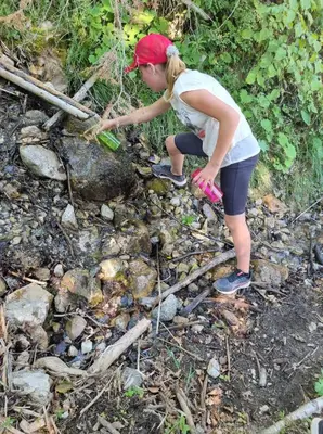 a woman is standing in a stream of rocks at Črjanski Raj in Črna na Koroškem