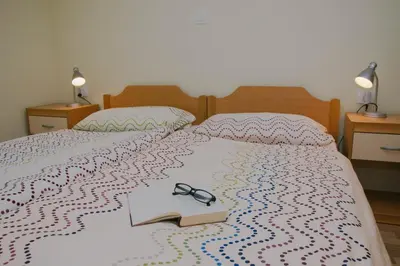 a bed with a book and glasses on it at Rooms Pri Lovrižu in Kobarid