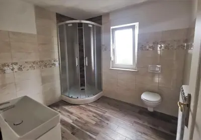 a bathroom with a shower and a toilet and a window at Rooms Jurca in Postojna
