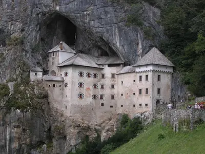 a castle built into a rock wall on a mountain at Rooms Jurca in Postojna