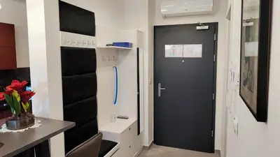 a hallway with a black door and a kitchen with a table at Apartment Ozare in Slovenj Gradec