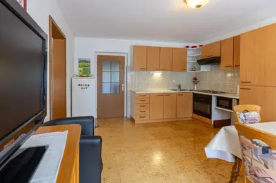 a kitchen with wooden cabinets and a white refrigerator at Apartmaji Arh Matilda in Bohinj