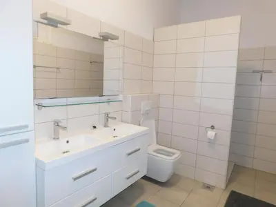 a white bathroom with a sink and a toilet at Yellow House Grabrovec in Metlika