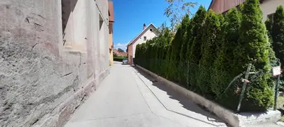 an empty alley with a fence and trees at Apartment Slovan in Škofja Loka