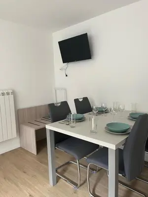 a dining room table with chairs and a tv on the wall at Apartma Melinc in Bovec