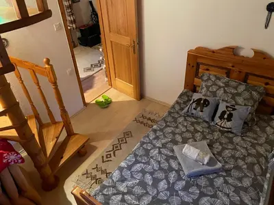 a small bedroom with a bed and a staircase at Hiša pod Rogatcem in Luče