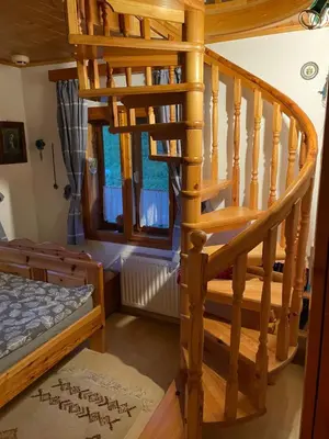 a wooden staircase in a room with a bed at Hiša pod Rogatcem in Luče